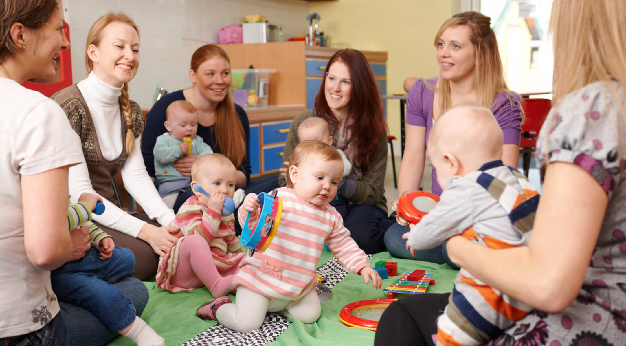 Moms with their kids sitting on the floor in a group circle