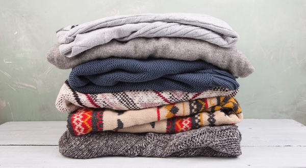 stack of folded sweaters against plain background