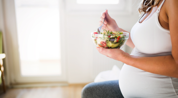 Pregnant woman sitting down eating a salad