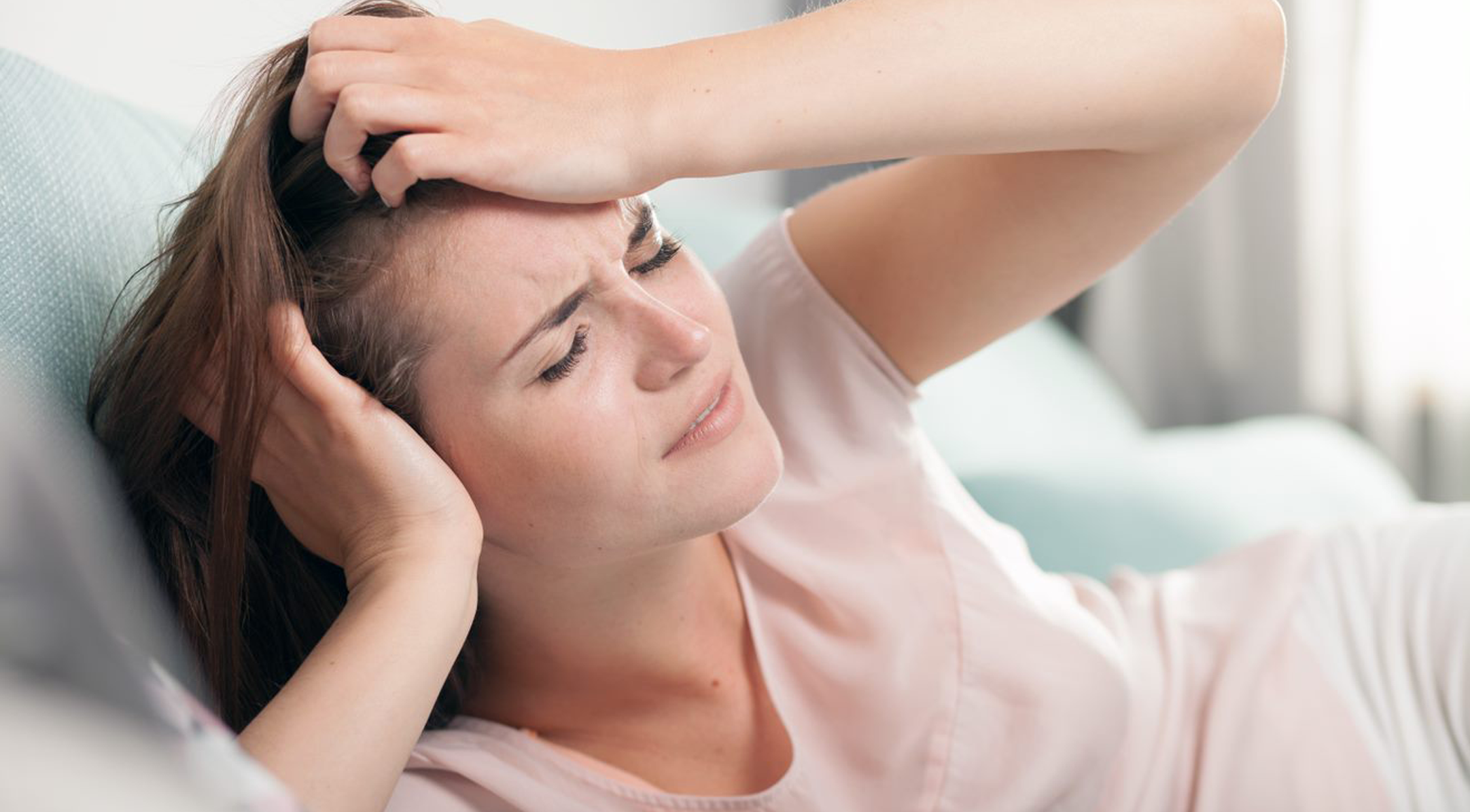 Woman lying down holding head in pain
