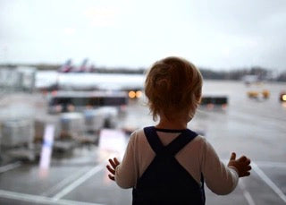 Childs back facing viewer as child looks outside of airport window