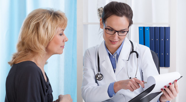Woman standing next to and looking over chart with Doctor