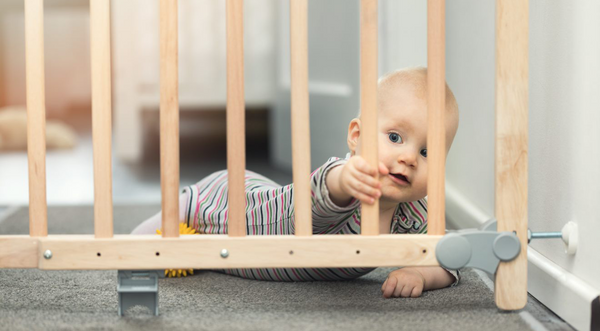 Baby holding onto a baby gate