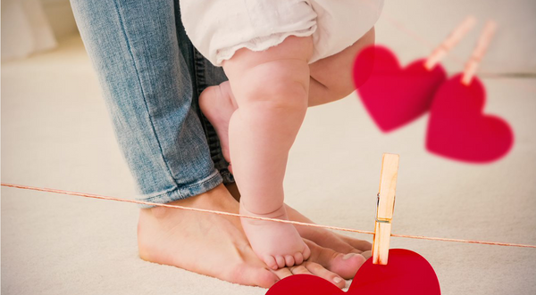 baby being held to stand on top of moms feet